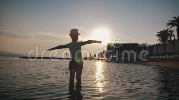 幸福的女孩的剪影站在夕阳的天空和大海的背景上暑假收养和人的概念视频的预览图