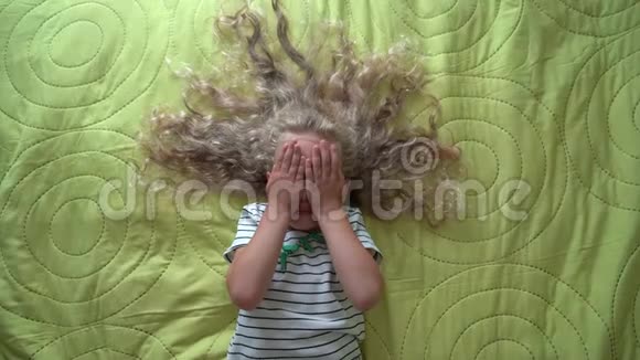金发小女孩躺在床上玩捉迷藏万向节运动俯视图视频的预览图