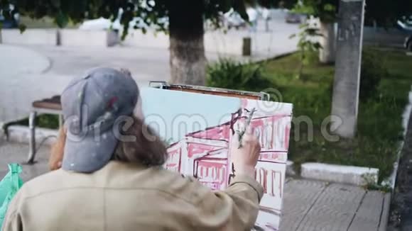 街头艺术家画一幅风景画从艺术家后面看视频的预览图