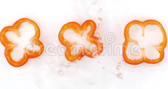 俯视图三片红色甜椒用水在白色背景上洗净水在缓慢运动中飞溅视频的预览图