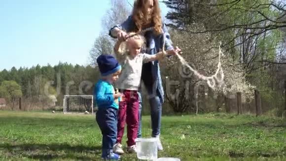 妈妈带着儿子和女儿在公园里吹泡泡万向节运动视频的预览图