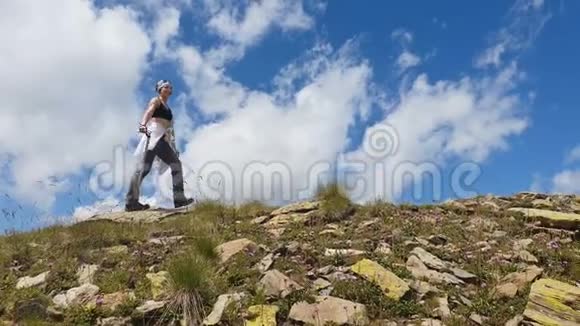 女登山运动员走着微笑着举起双手站在懒懒的山上视频的预览图