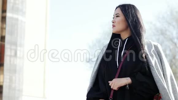 美丽的年轻亚洲女孩留着长长的黑发站在街上视频的预览图