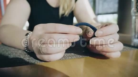 女孩拉着橡皮筋的手做头发她坐在咖啡馆的一张桌子旁等着点菜视频的预览图