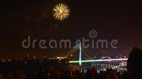 夜城灯火通明的桥上围观节日烟火的人群视频的预览图