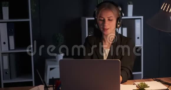 女商人在夜间办公室一边听音乐一边唱歌视频的预览图