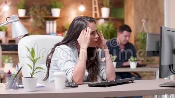 精疲力竭压力大头痛的妇女在繁忙的办公室工作视频的预览图