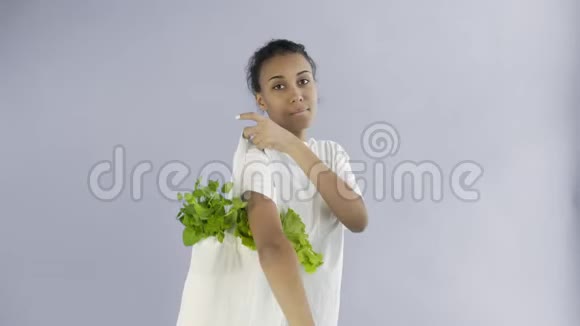 女人拿着灰色背景的蔬菜包视频的预览图