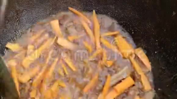 烹饪食物胡萝卜肉在煮沸的肉汤中煮沸厨师把配料混合在一个铸铁锅里特写镜头牛肉视频的预览图