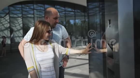 夫妇站在现代建筑中使用电子信息板站在街上交互式屏幕视频的预览图