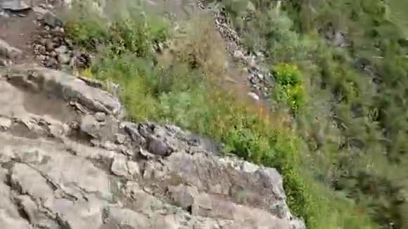 第一人称观点在山上远足一条穿过岩石地形的小径危险的道路在山的边缘公鸡草视频的预览图