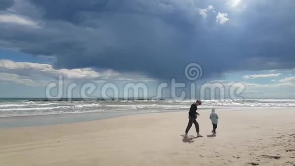 母亲和女儿在春天的沙滩上散步视频的预览图