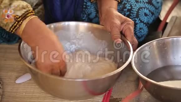东方女人的老女人的手在一个大盘子里揉面团视频的预览图