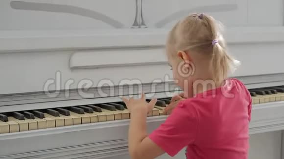 一个坐在白钢琴旁的小女孩按下键视频的预览图