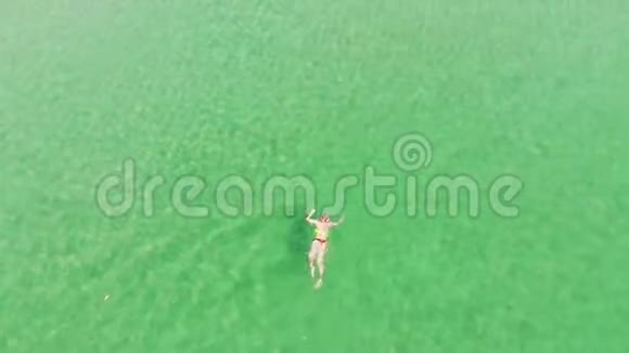 在清澈透明的海水中俯视女性鸟瞰女人在绿松石海水带水晶的天堂海滩视频的预览图