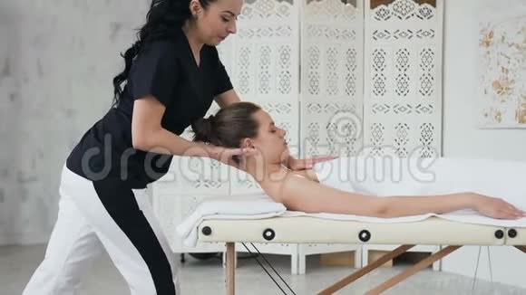 女性治疗师在白种人年轻女性的颈部做治疗按摩视频的预览图