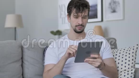 休闲青年在Couch放松平板电脑上的在线视频聊天视频的预览图