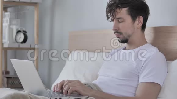 休闲青年在家中睡觉时使用笔记本电脑视频的预览图
