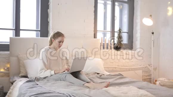 疲惫的女孩在床上使用笔记本电脑时放松伸展身体视频的预览图