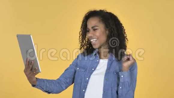 非洲女孩通过黄色背景下的平板电脑进行视频聊天视频的预览图