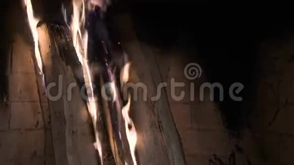 一堆木头烧在砖壁炉里黄色和紫色火焰的舌头视频的预览图