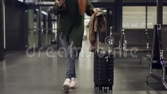 年轻女子穿过机场航站楼使用智能手机视频的预览图