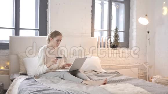 坐在床上的年轻女孩的网上购物视频的预览图