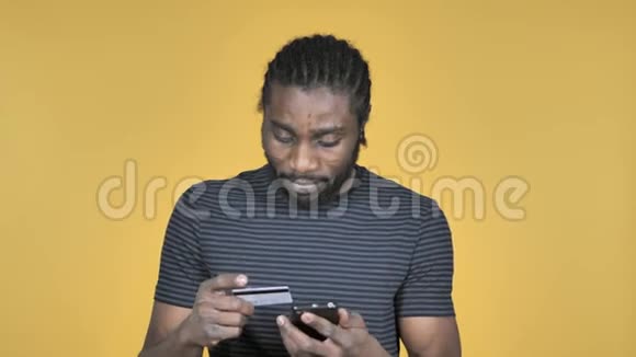 黄色背景下非洲男子在智能手机上的网上购物视频的预览图