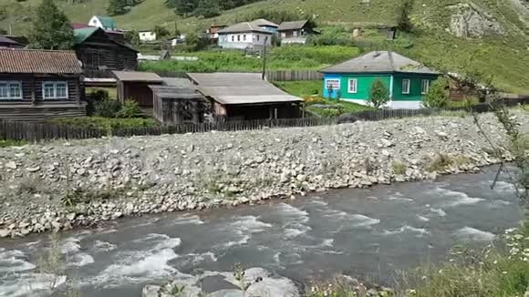 一条粗糙的小河岸边的旧木屋俄罗斯阿尔泰共和国的典型景观视频的预览图