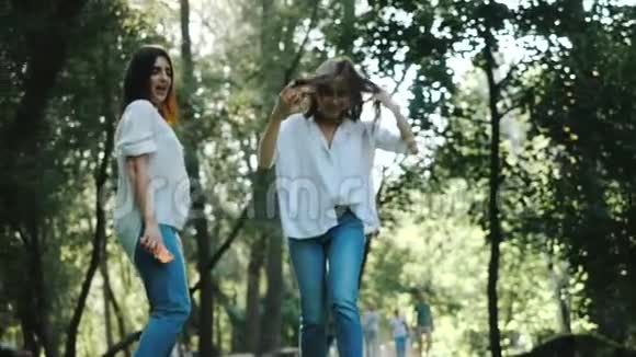两个快乐的年轻黑发女孩笑着慢动作跳舞快乐的女人头发随风飘动视频的预览图