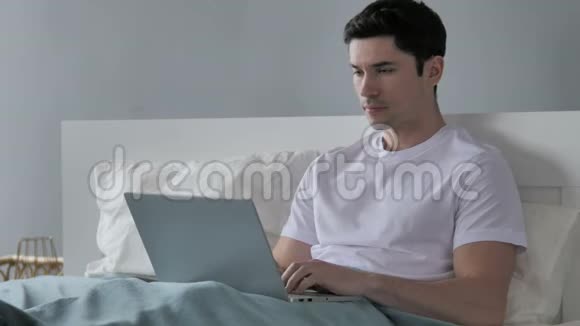 青年男子在床上工作时因丢失而心烦意乱视频的预览图