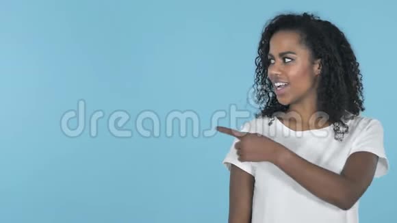 非洲女孩手指指向侧面蓝色背景视频的预览图
