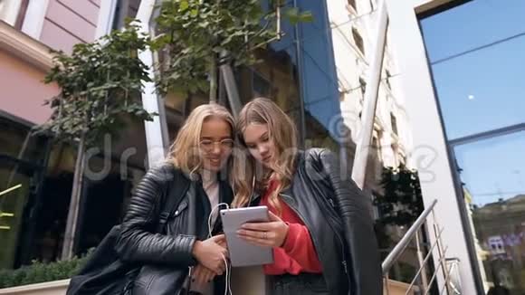 漂亮的两个女学生用平板电脑阅读好消息在愉快的午休时间视频的预览图