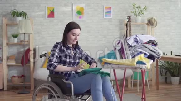 年轻的残疾妇女家庭主妇洗衣服做家务看着相机微笑视频的预览图