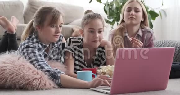 少女在家吃零食时在笔记本电脑上看媒体内容视频的预览图