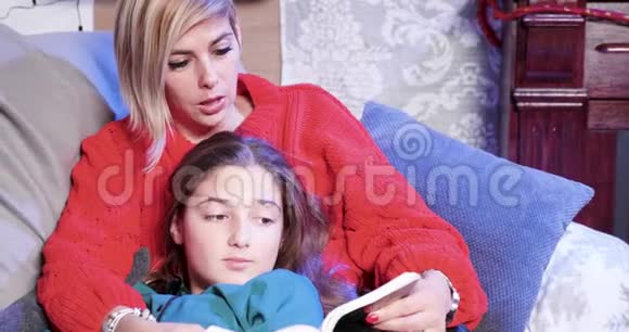 圣诞节前夕妈妈正在给小女儿读一本书视频的预览图