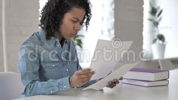 工作中创造性的非洲女孩阅读文件视频的预览图