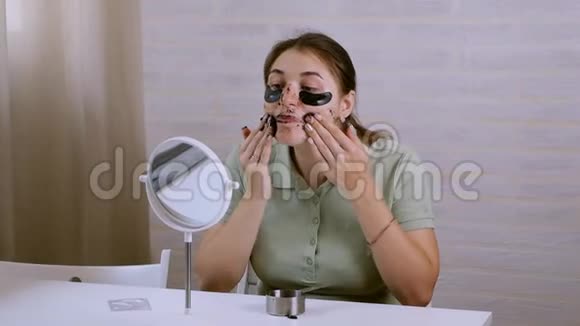 镜子附近的女孩在脸上做整容手术女孩把韩国化妆品放在她下面的区域视频的预览图