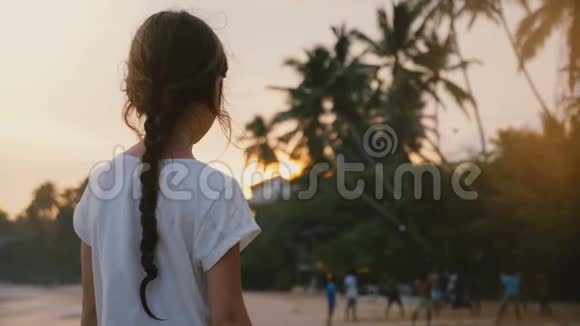 美丽的后景拍摄小68岁的快乐女孩在热带异国情调的海边看日落和人视频的预览图