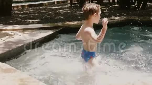 镜头在快乐的四六岁白人男孩周围移动在一个阳光明媚的夏天游泳池里用手臂泼水视频的预览图