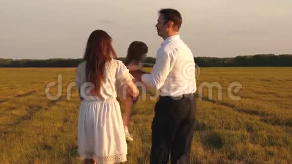 快乐的爸爸抱着一个小女儿在他的怀里和他的妈妈在田里玩父母和孩子一起玩视频的预览图