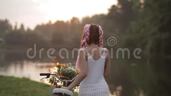 美丽的女孩有时尚的发型在公园里骑自行车散步视频的预览图