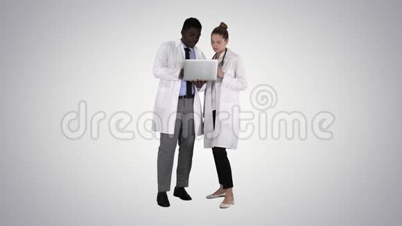 医务人员在灰色笔记本电脑前工作同时站在梯度背景上视频的预览图