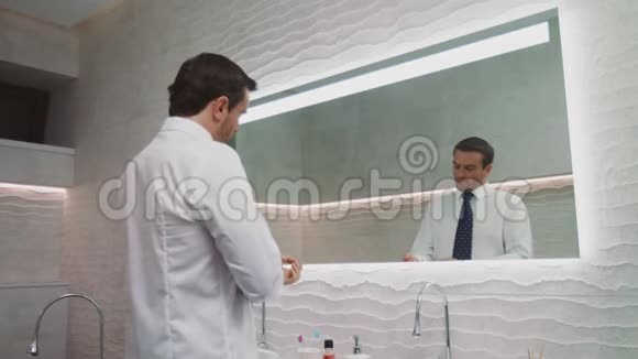 商人在豪华浴室系领带在家里戴领带的快乐男人视频的预览图