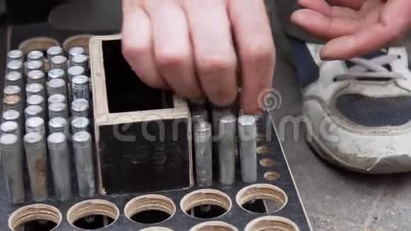 工人手把圆筒状的金属别针放进有圆孔的木箱里视频的预览图