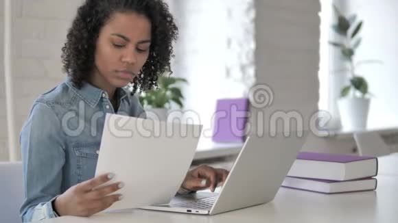创造性的非洲女孩阅读文件和笔记本电脑工作视频的预览图