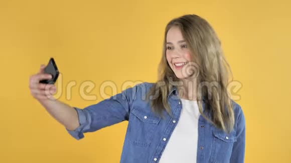 黄色背景下带智能手机的年轻美女视频的预览图