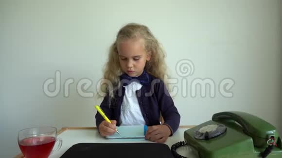 金发女孩扮演秘书孩子坐在桌子旁带着复古手机万向节运动视频的预览图