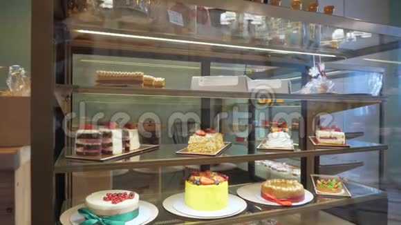 玻璃架子上有蛋糕和糕点的面包店视频的预览图