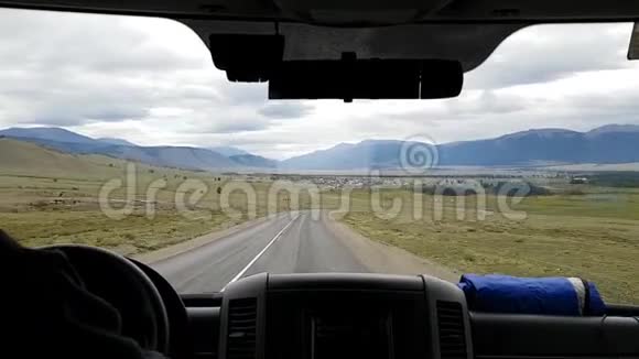在观光之旅中在蛇形公路上的草原上通过汽车的前窗观看视频的预览图